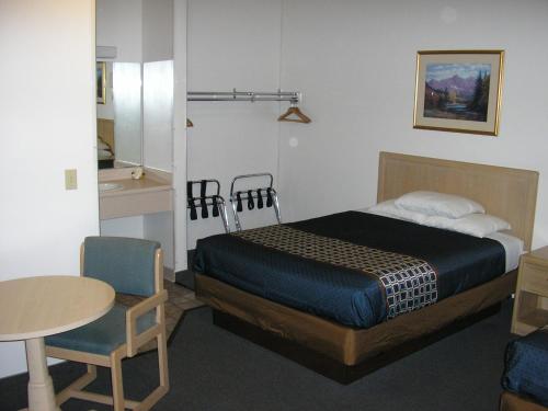科罗拉多斯普林斯Mecca Motel的卧室配有1张床和1张桌子及椅子