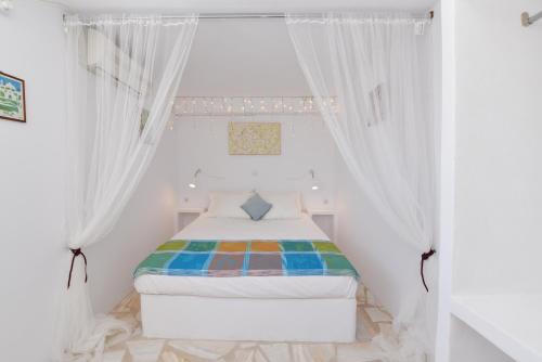 梅加斯·亚洛斯-奈特斯VILLA PETROS SEA SUITE的一间白色的小卧室,配有带窗帘的床