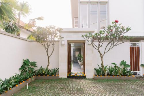 努沙杜瓦Kubu Benoa Guest House的白色的房子,有门和树木