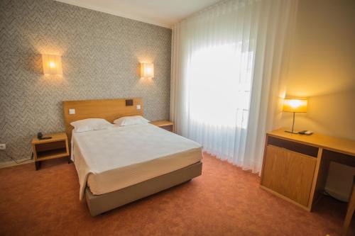 孔迪镇Hotel Brazão的一间卧室设有一张床和一个大窗户
