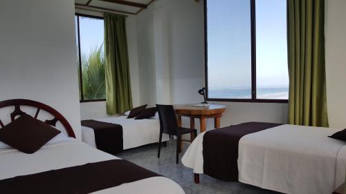 比亚米尔港Hotel La Jungla的酒店客房设有两张床、一张书桌和窗户。