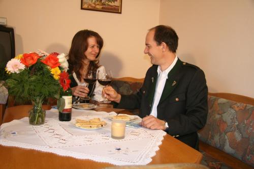 MiesenbachBio-Bauernhof Wilfling的坐在桌子旁喝一杯酒的男人和女人