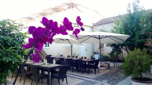 AlesAbas Ristorante Pizzeria Affittacamere的一个带桌子和遮阳伞及紫色鲜花的庭院