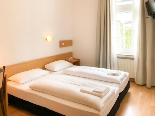 杜塞尔多夫月亮酒店的一间带两张床的卧室,位于带窗户的房间内