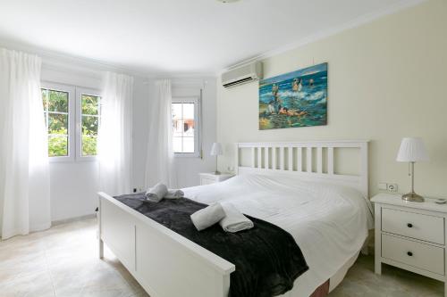 德尼亚珊瑚别墅的白色卧室设有一张大床和两个窗户
