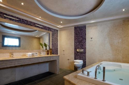费拉佩提宫套房酒店的带浴缸、卫生间和大镜子的浴室