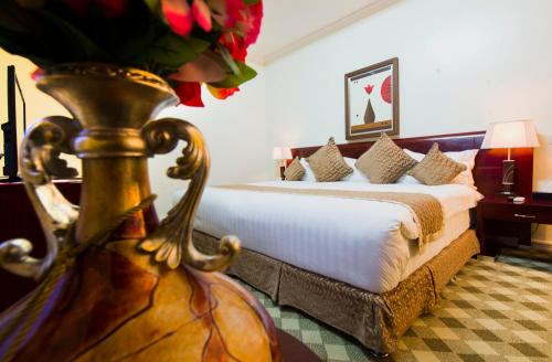 基加利The Manor Hotel的配有一张床和花瓶的酒店客房