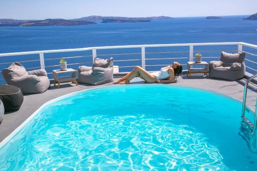 伊亚白珍珠别墅酒店的坐在游泳池旁甲板上的女人