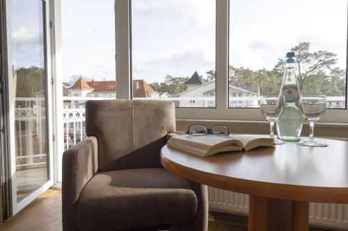 巴贝R&R Villen Baabe的一张桌子,上面放着一本书,放着眼镜和一瓶葡萄酒