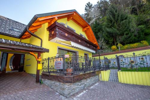 贝古耶·纳·格伦奇克Rooms Močilnik的黄色房屋设有阳台和围栏