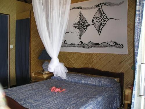 波拉波拉特曼努阿塔乡村酒店的一间卧室配有一张带窗帘和粉红色鲜花的床。