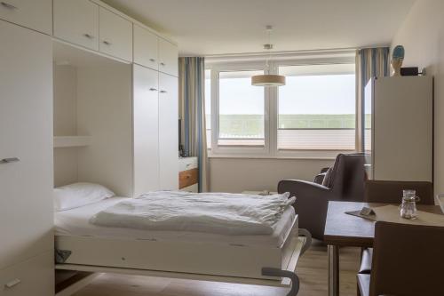 库克斯港Strandhaus Christiansen的一间卧室配有一张床、一张书桌和一个窗户。