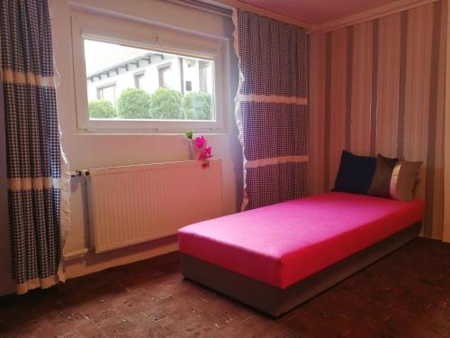 波莫瑞地区德拉夫斯科Apartament Wiki的一间小房间,窗户前设有一张粉红色的床