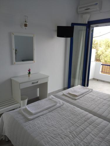 斯卡拉Hotel Poulakis的白色卧室配有床和镜子