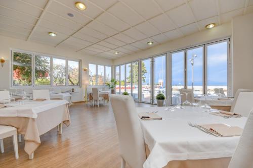 加达湖畔帕登赫Hotel Villa Garuti的餐厅设有白色的桌椅和窗户。