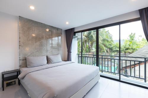 芭东海滩Minimal House Patong的一间卧室设有一张大床和一个大窗户