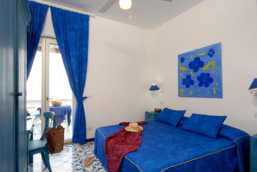 伊斯基亚Hotel La Sirenella的一间卧室设有蓝色的床和窗户。
