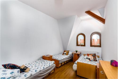 什切青Strych Kościuszki - duży的配有白色墙壁和木地板的客房内的三张床