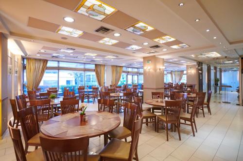 雅典水晶之城酒店的餐厅设有木桌、椅子和窗户。
