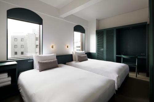 东京DDD HOTEL的带2扇窗户的酒店客房内的2张床