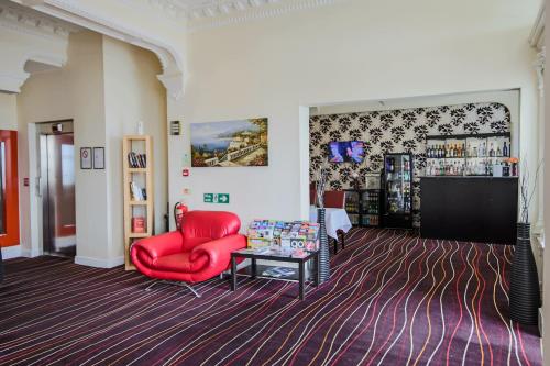 兰迪德诺Iris Hotel Llandudno的客厅配有红色椅子和桌子
