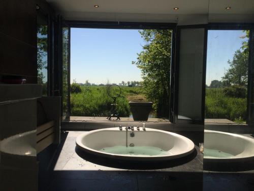 VijfhuizenBungalow between Haarlem and Amsterdam with a large bubble bath的享有田野景致且带大浴缸的浴室