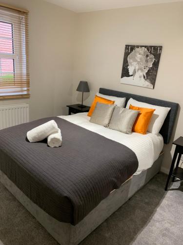 贝尔法斯特4 bed Duplex Apartment, Belfast的一间卧室配有一张大床,提供橙色和灰色的枕头