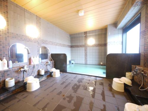 福井福井站前酒店的浴室设有游泳池、两个盥洗盆和镜子