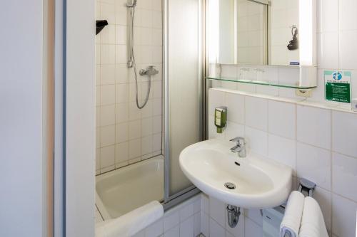 曼海姆中心大酒店的白色的浴室设有水槽和淋浴。