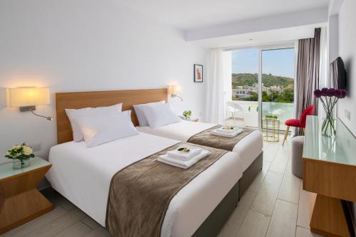 普罗塔拉斯Kokkinos Boutique Hotel的酒店客房设有两张床和大窗户。