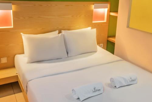 雅加达塞纳扬拉格林套房酒店的一张带白色床单和枕头的床
