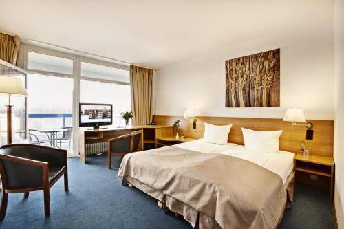 布隆Hotel Plöner See by Tulip Inn的配有一张床和一张书桌的酒店客房
