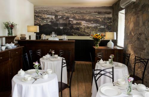 Torrechiara罗坎达德尔博尔戈酒店的一间设有白色桌椅的餐厅,