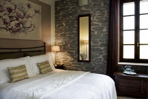 Torrechiara罗坎达德尔博尔戈酒店的卧室配有白色的床和石墙