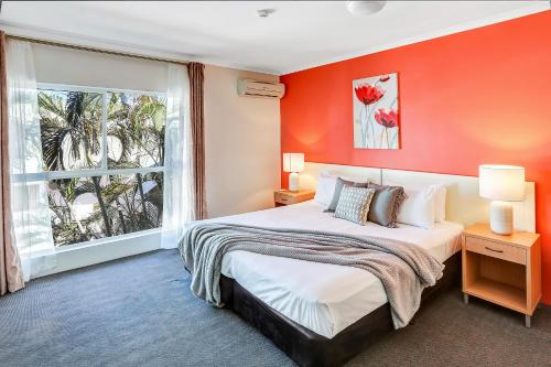 凯恩斯珊瑚树酒店的一间卧室配有一张带橙色墙壁的大床