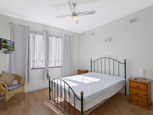 安特兰斯The Sands Apartment 6的一间卧室配有一张床、一把椅子和吊扇