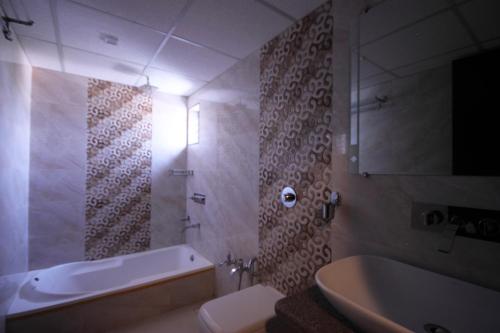 艾哈迈达巴德Hotel Furaat Inn的带浴缸、卫生间和盥洗盆的浴室