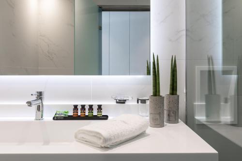卡拉马塔Messinian Icon Hotel & Suites的浴室配有带镜子的盥洗盆和毛巾