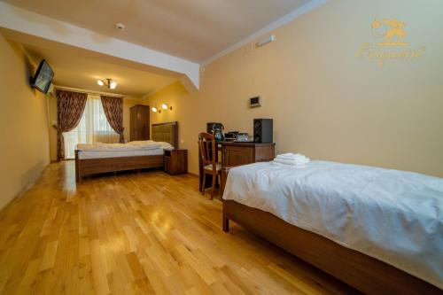 德瓦Villa Etiquette的酒店客房设有两张床、一张桌子和一张书桌。