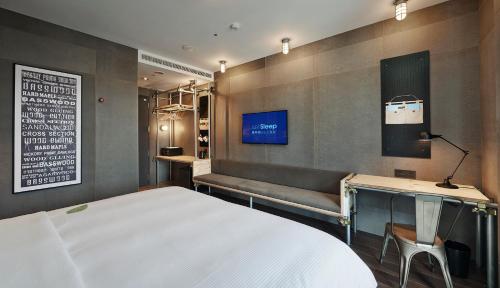 台北捷丝旅台北三重馆的一间卧室配有一张床、一张长凳和一台电视。