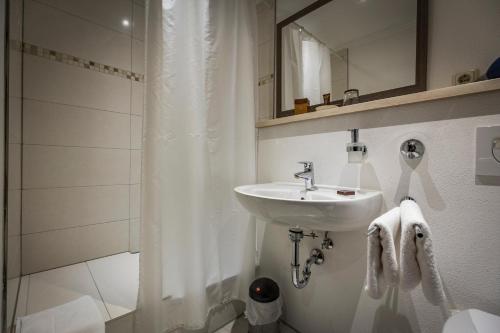 巴特莱辛哈尔Kurhotel Falter的白色的浴室设有水槽和淋浴。