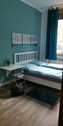 柏林Pension Kaffeefreunde的一间卧室配有一张床、一张桌子和一面蓝色的墙壁