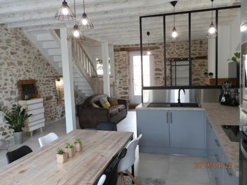 MauléonGITE IZALIN AVEC SPA A 20 min du Puy du Fou的厨房以及带木桌的起居室。