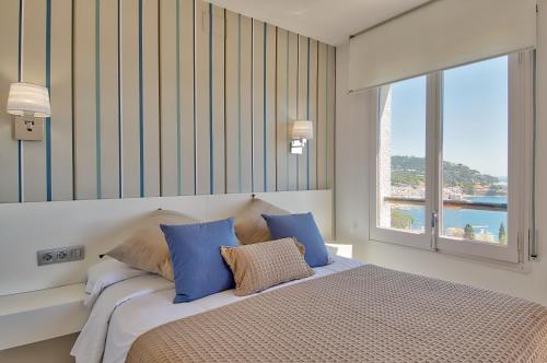 卡莱利亚德帕拉弗鲁赫尔Panoramic Sea Views的一间卧室配有一张带蓝色枕头的床和一扇窗户。