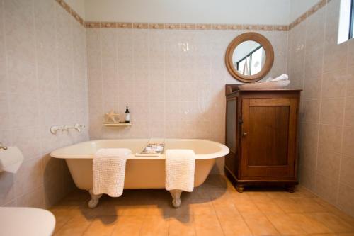 古尔瓦Boathouse - Birks River Retreat的带浴缸和镜子的浴室