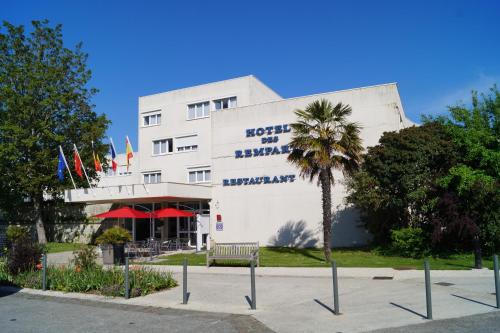 罗什福尔Hôtel & Restaurant des Remparts的一座白色的建筑,前面有棕榈树