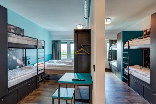 慕尼黑MEININGER Hotel München Olympiapark的客房设有三张双层床和一张桌子。