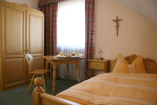 莫星宁Landgasthof Stangl的一间卧室配有一张床和一张桌子,窗户上有一个十字架