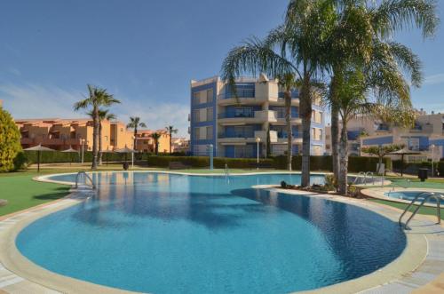 卡布罗伊格Cabo Roig - Blue Luxury Apartment的一座棕榈树大型游泳池和一座建筑