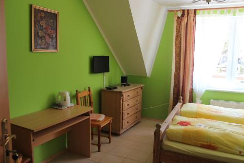波别罗沃Pension Dom Wypoczynkowy Ulla的一间卧室设有绿色的墙壁、一张桌子和一张床